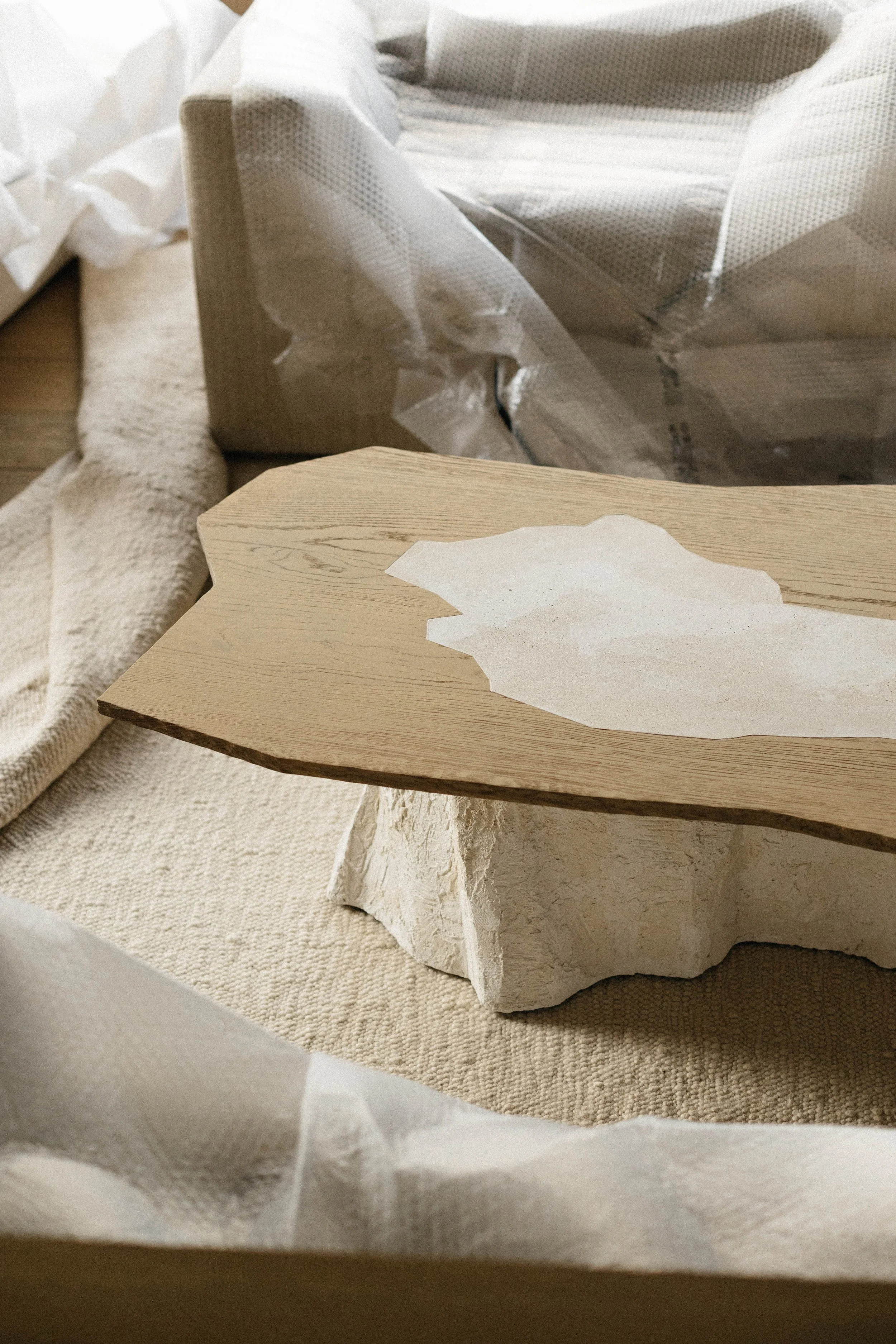 Un objet en bois en cours d'installation ou de peinture, placé sur un tissu blanc ou une nappe beige, avec du papier autour.