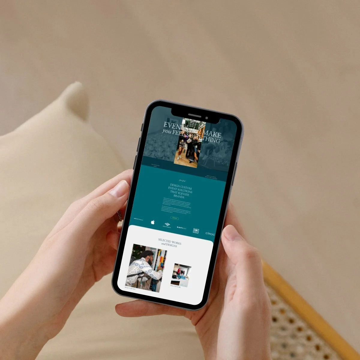 Person holding a smartphone displaying a website or app related to event planning and design, with images of people and text about custom event solutions.