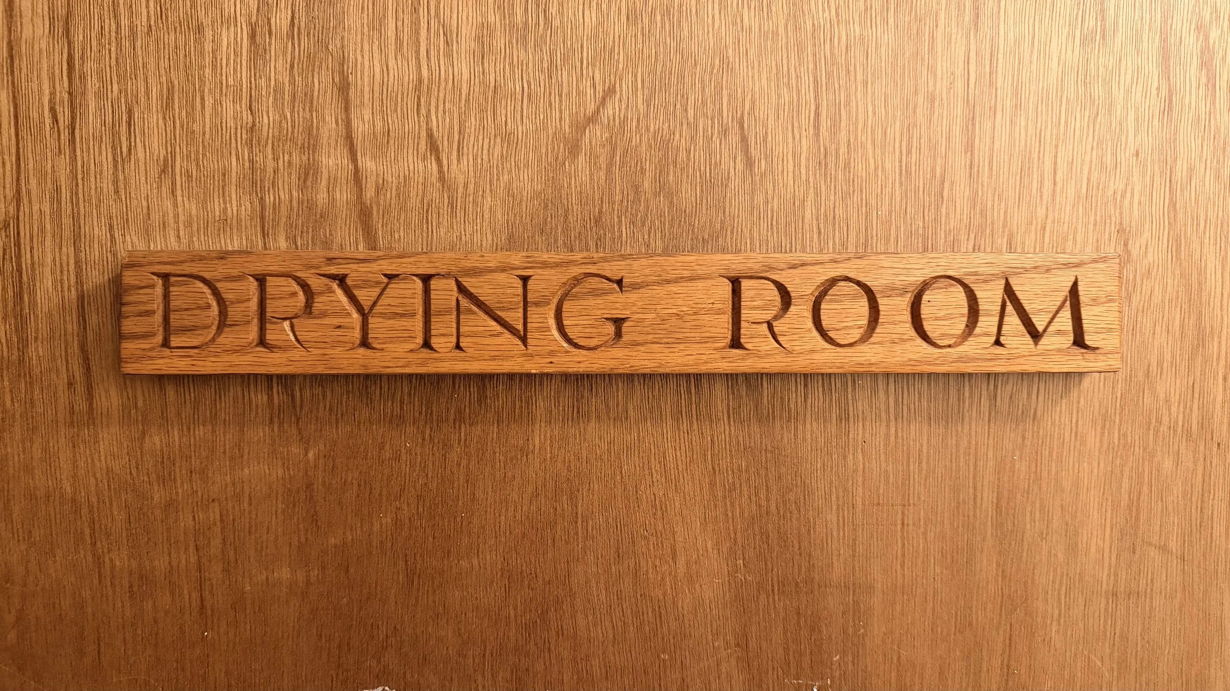 Carved wooden 'Drying Room' sign at Newtonmore Hostel — somewhere for wet boots and waterproofs after a Highland walk