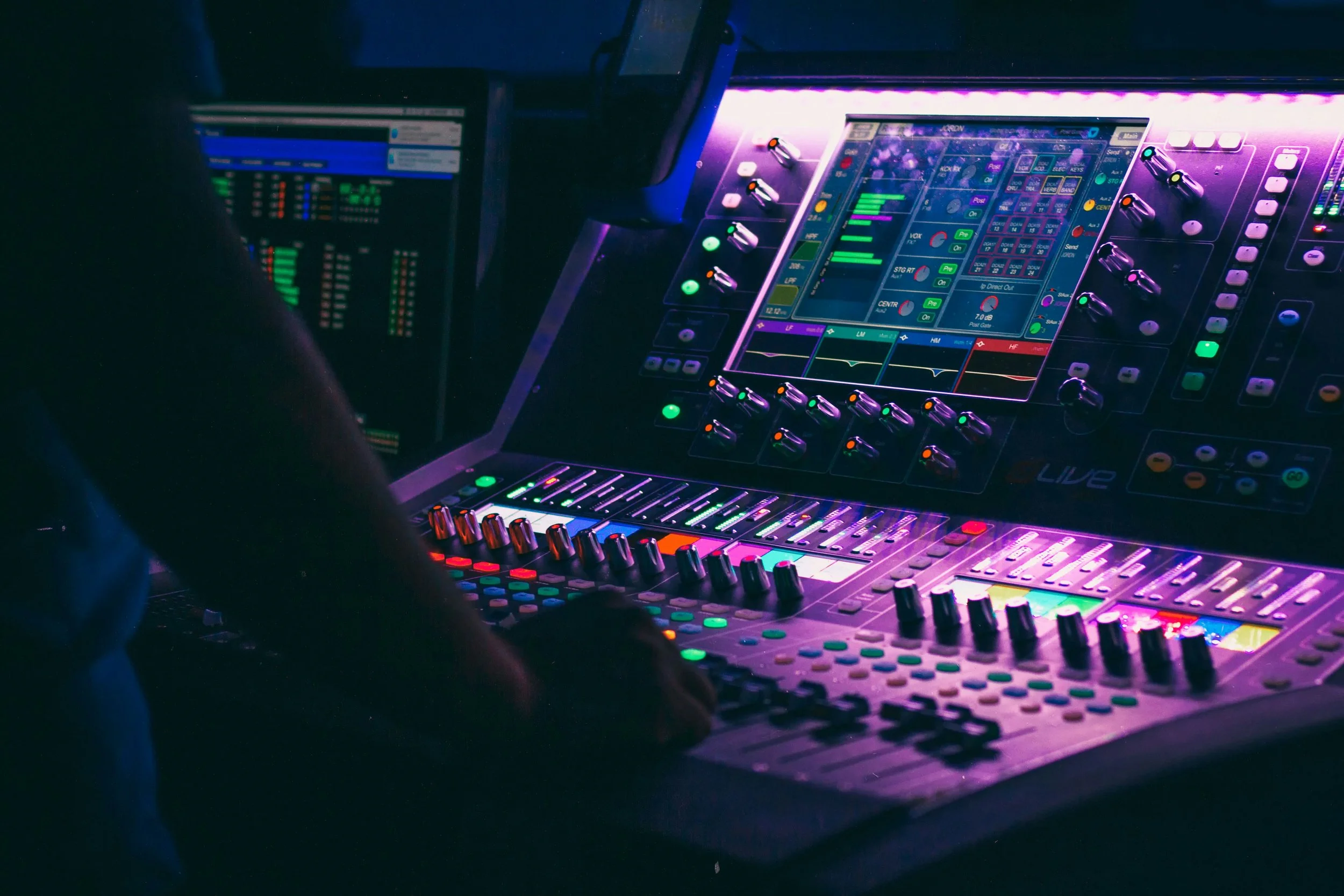 Close-up of a digital DJ mixing console with colorful illuminated buttons and knobs in a dark environment.