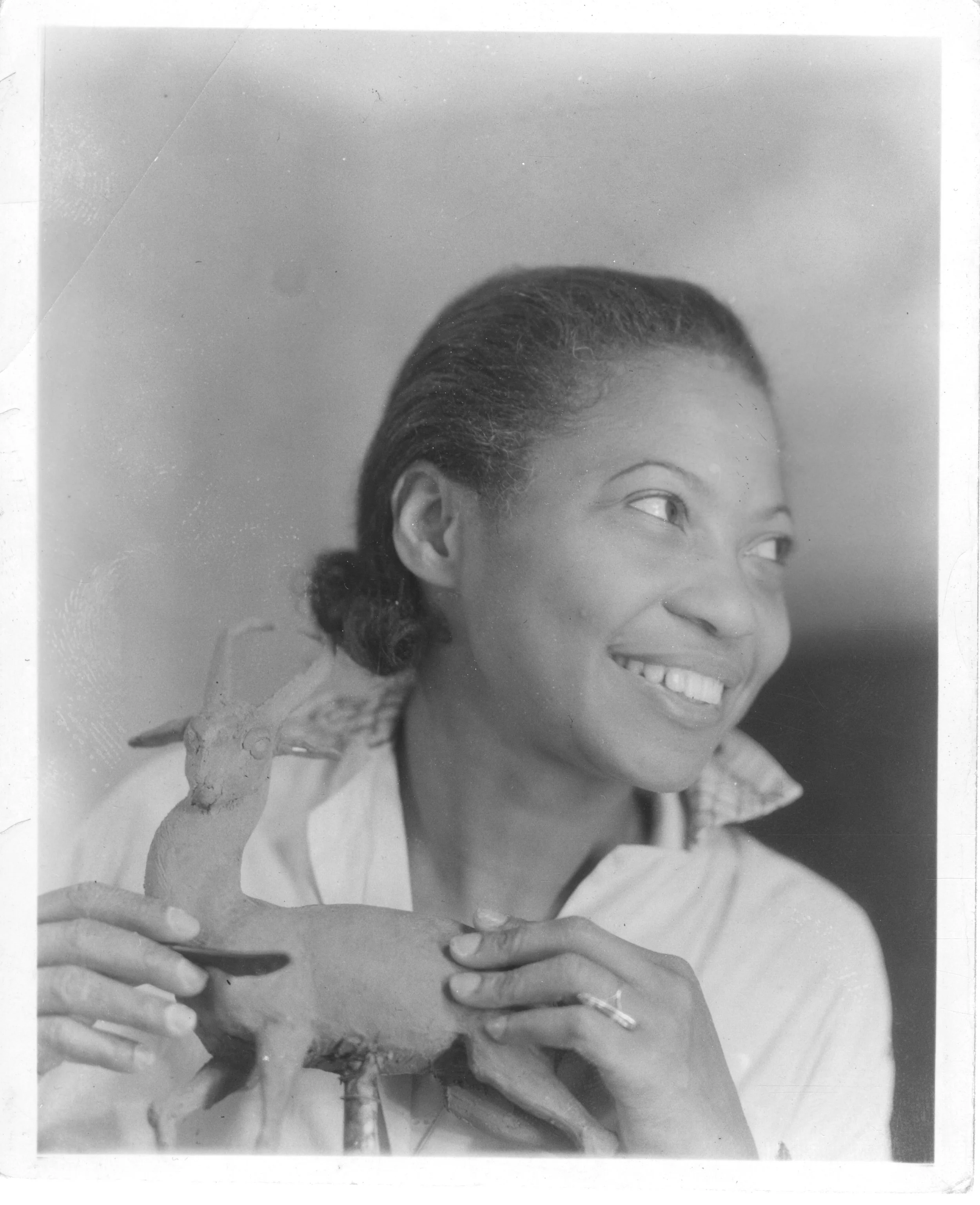 Augusta Savage shaping a small clay animal figure by hand. Modeling in clay was her earliest medium, dating to her childhood in Florida.