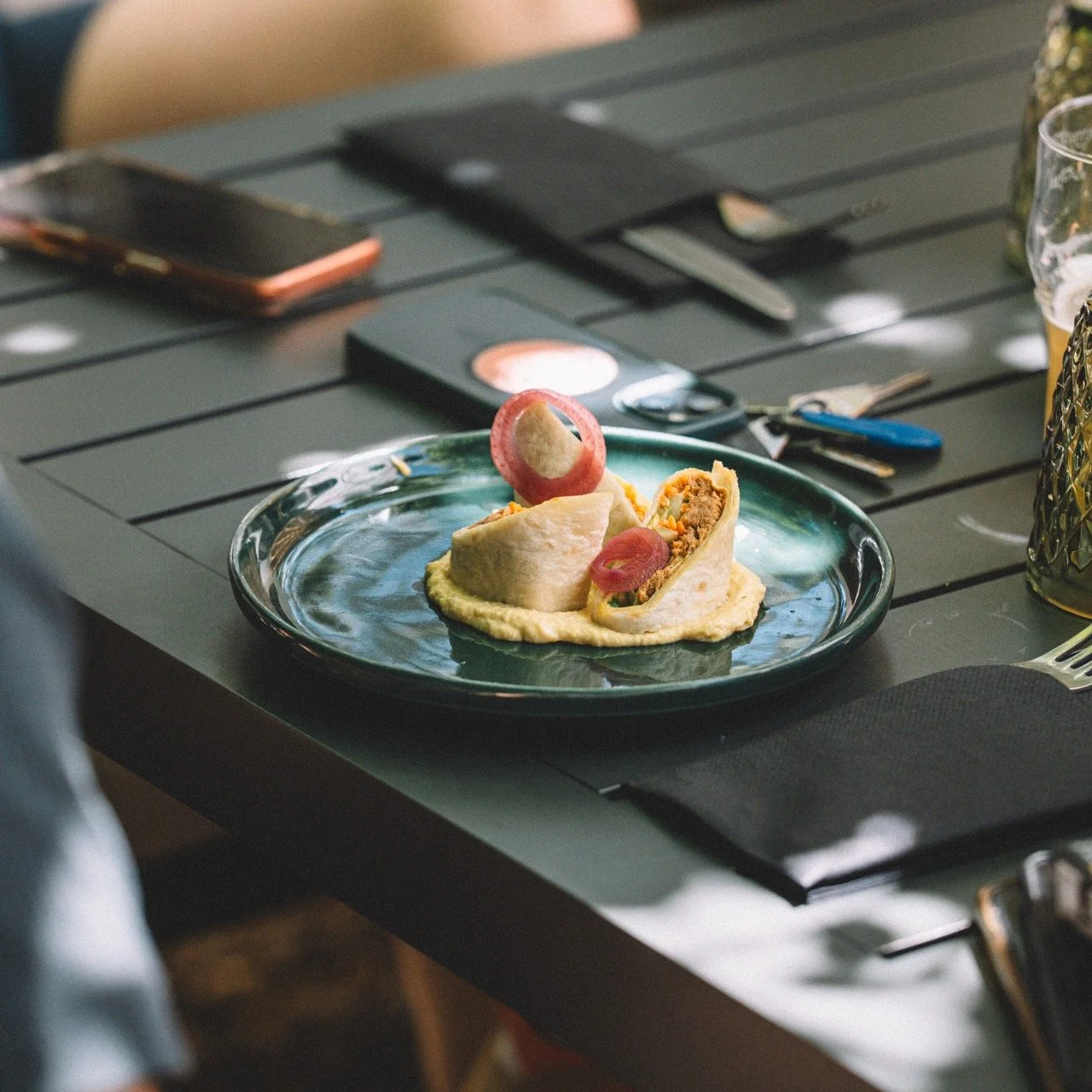 Assiette avec un wrap coupé en deux, garnie de légumes et de viande, garnie de tranches de radis, sur une table à manger.