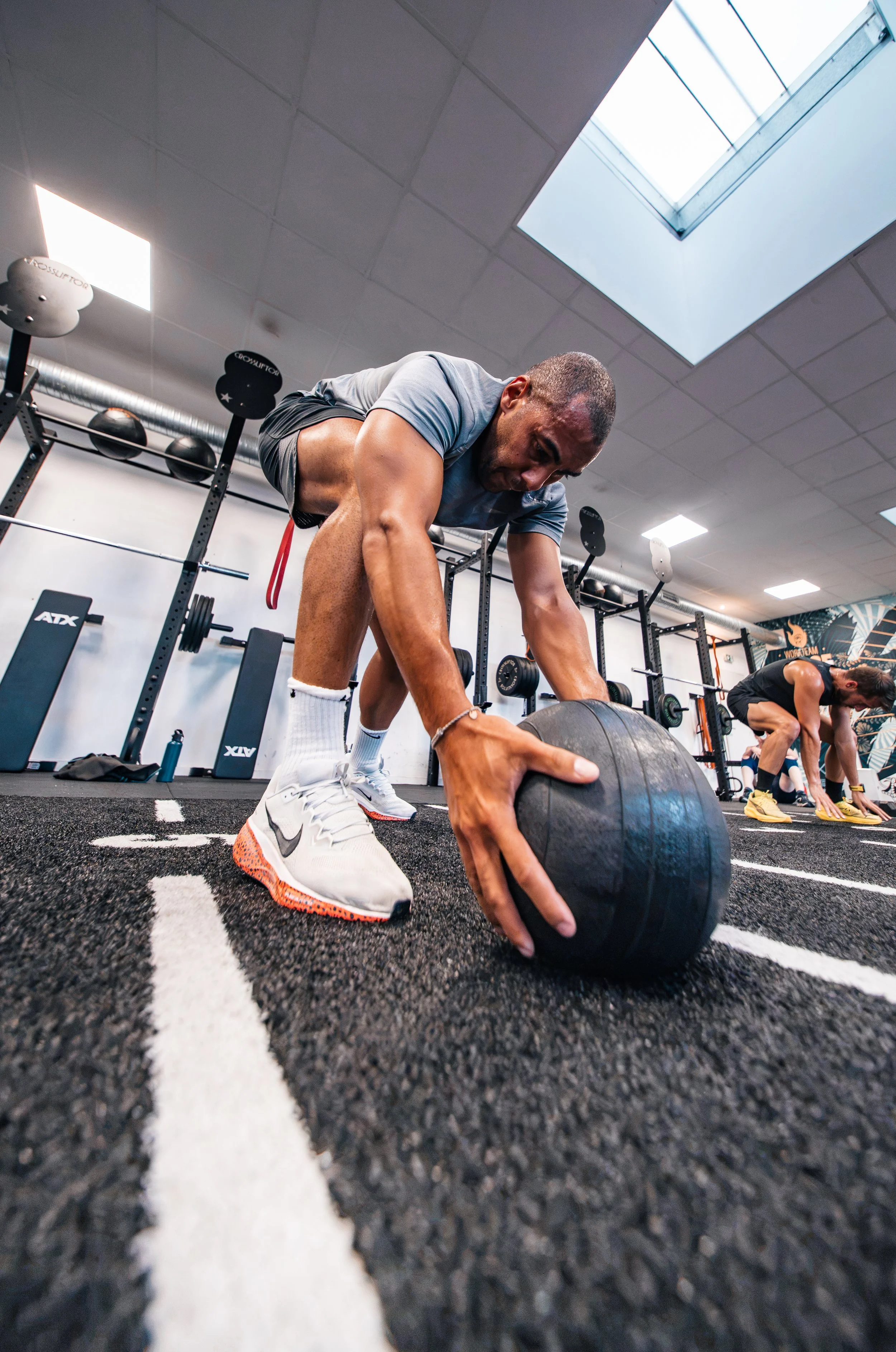 Un homme en train de faire un entraînement de musculation avec une roue en salle de sport, avec un plafond avec un panneau solaire au plafond.