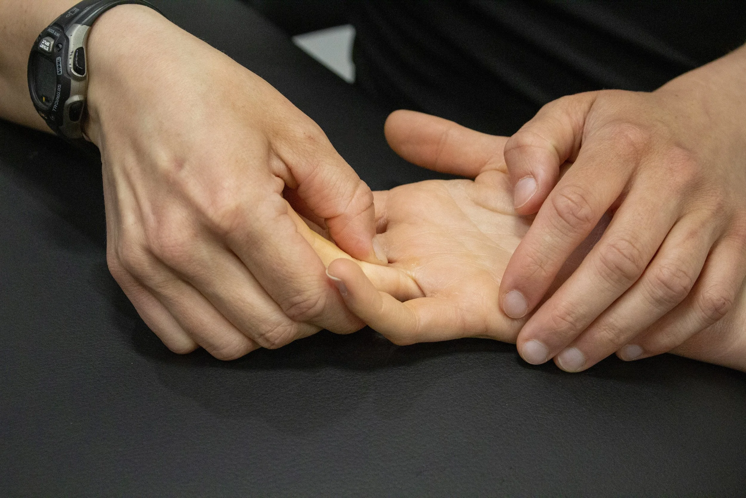 Physical Therapist palpates patient's finger