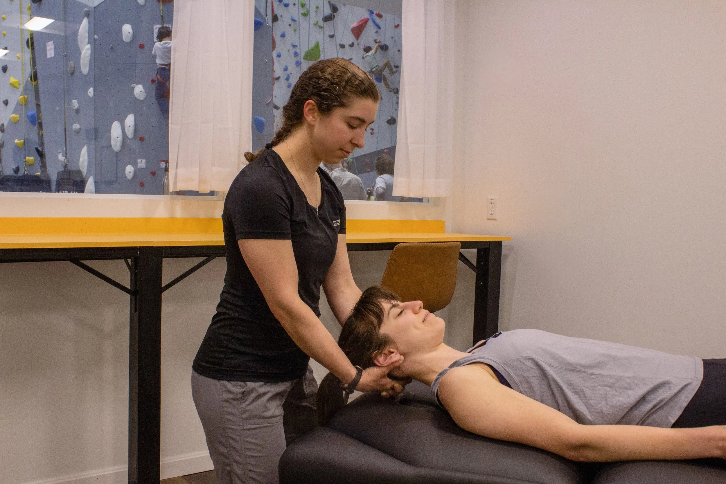 Patient laying on treatment table, physical therapist holds patient's head, performing cervical distraction