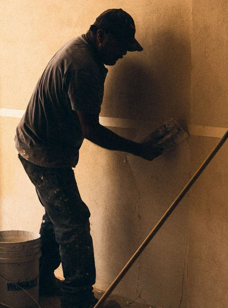 Persona aplicando cemento en la esquina de una pared interior.
