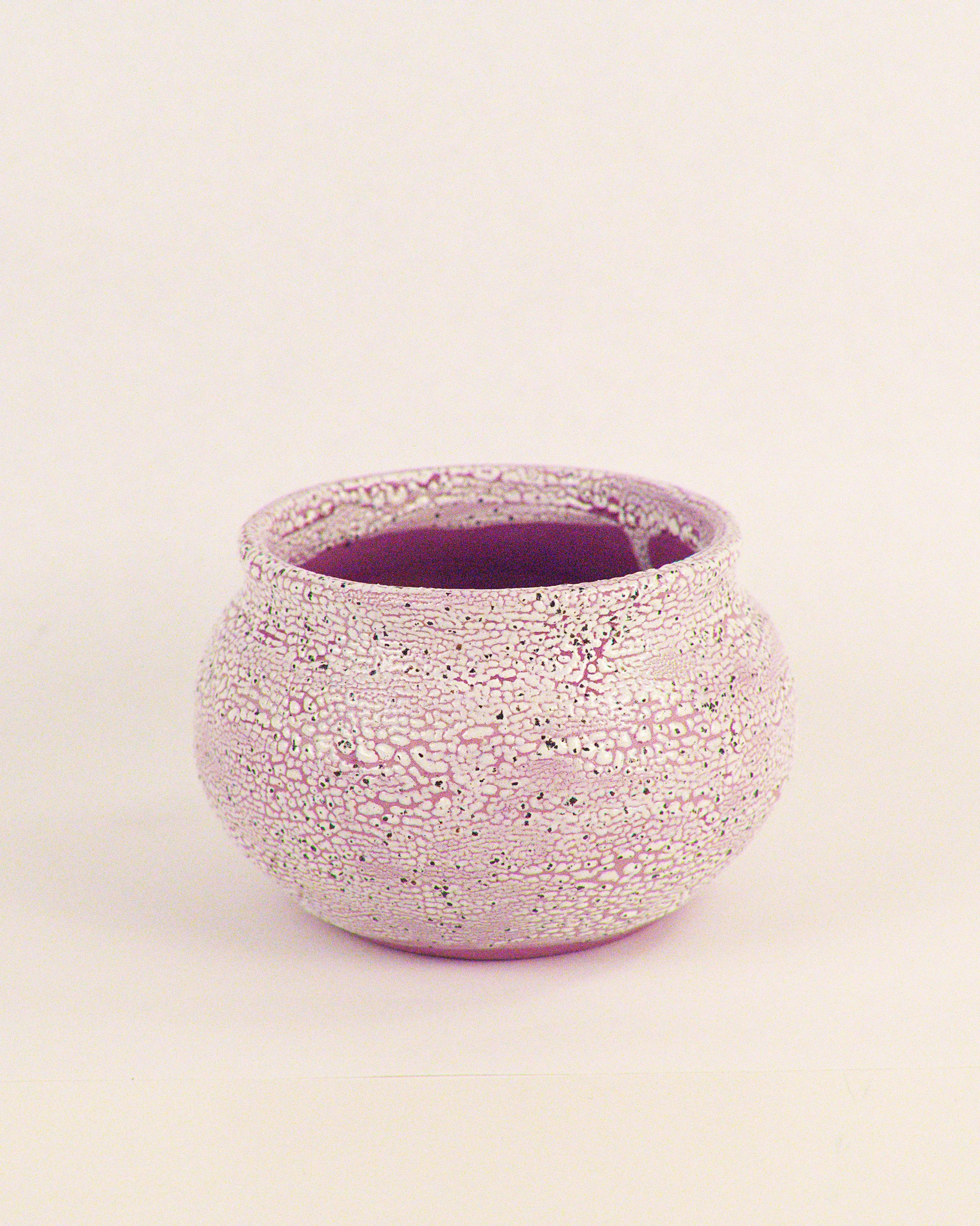 Purple and white textured ceramic pottery vase with a rounded shape against a plain light background.