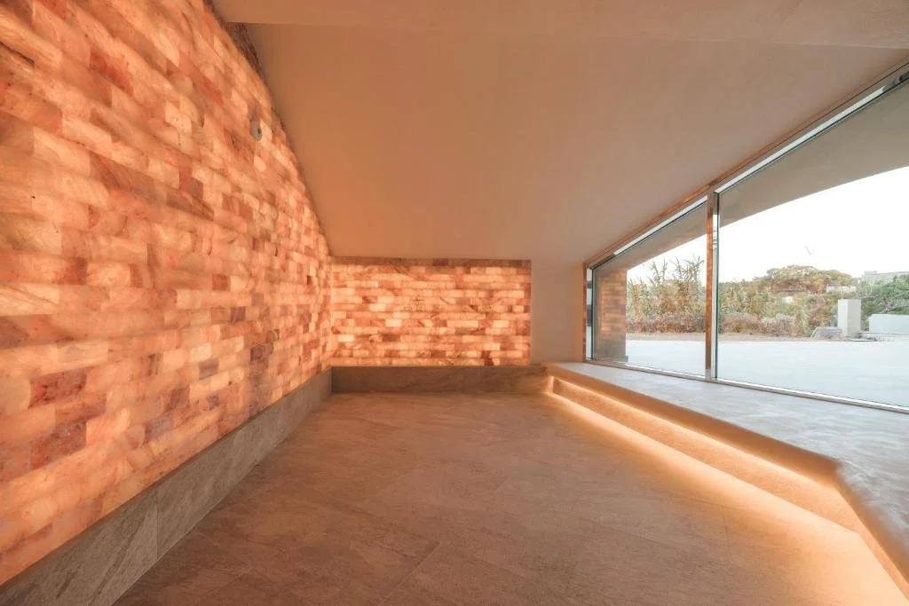 Modern interior room with a brick accent wall, wooden flooring, large floor-to-ceiling windows, and a cityscape view outside.