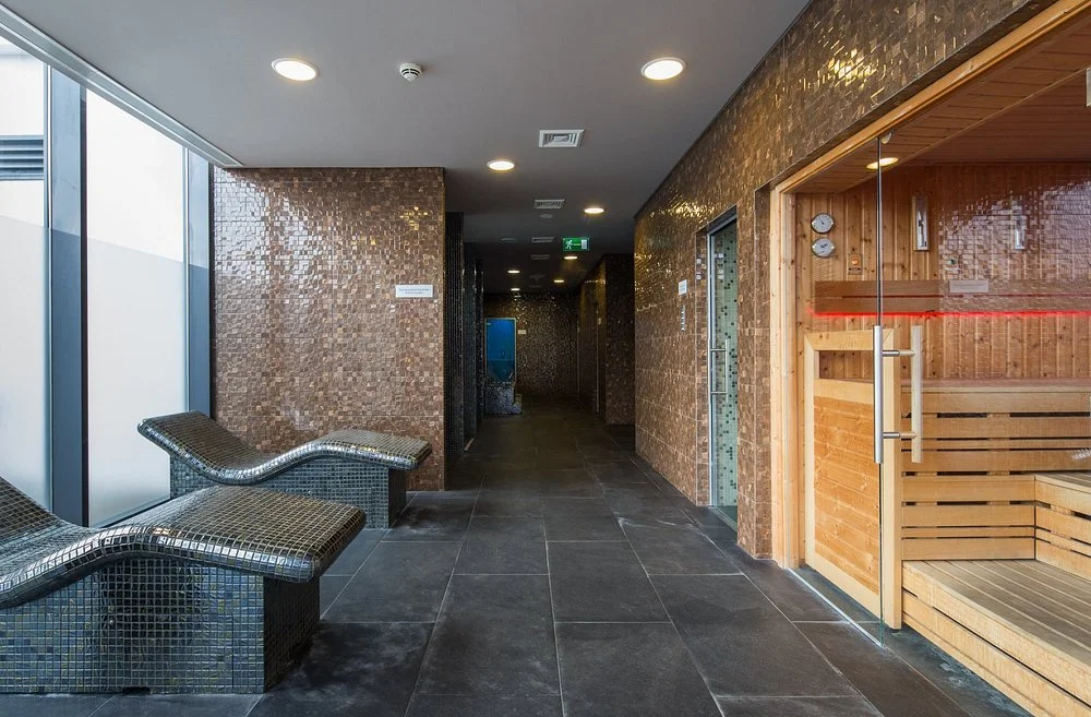 Indoor spa area with a loon sauna and seating area, tiled walls, and large windows.