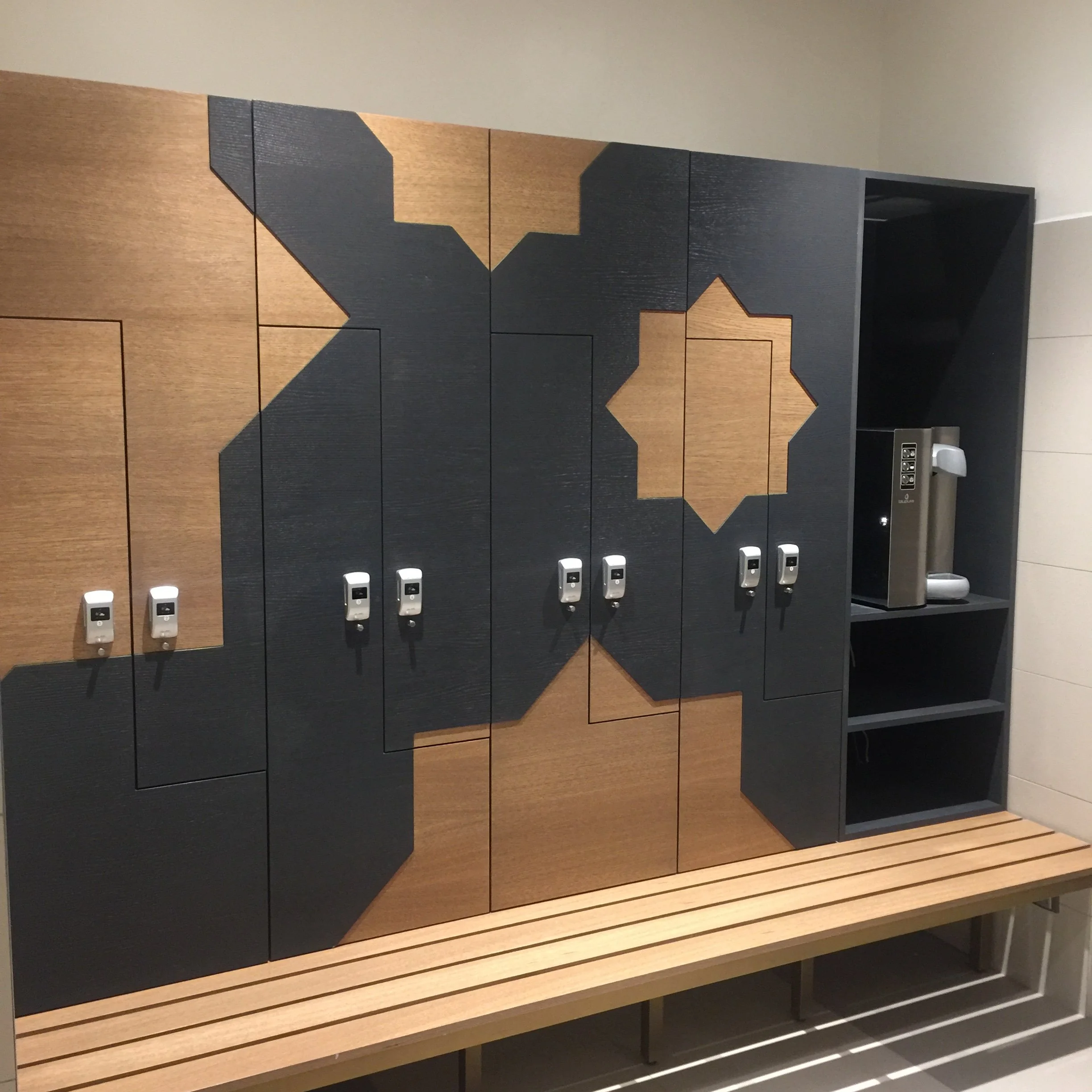 Wooden benches with decorative black accents and hooks, located in an indoor public space, possibly a waiting area or lobby.
