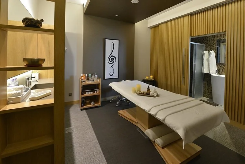 Spa treatment room with massage table, candles, and decor.