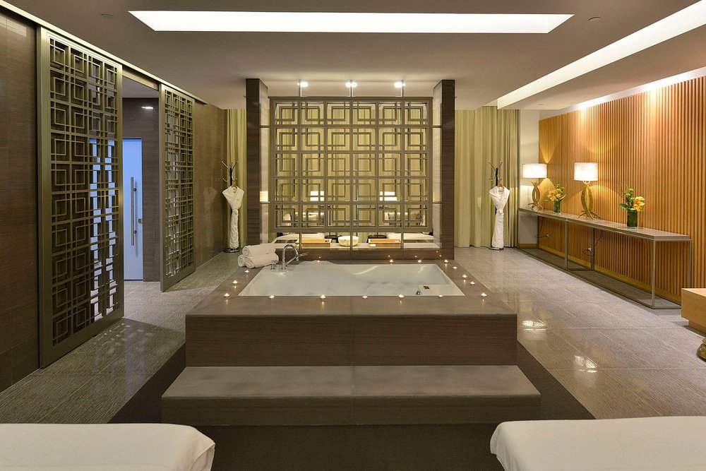 Luxury hotel spa with hot tub, modern decor, warm lighting, decorative vases, and wooden accents.