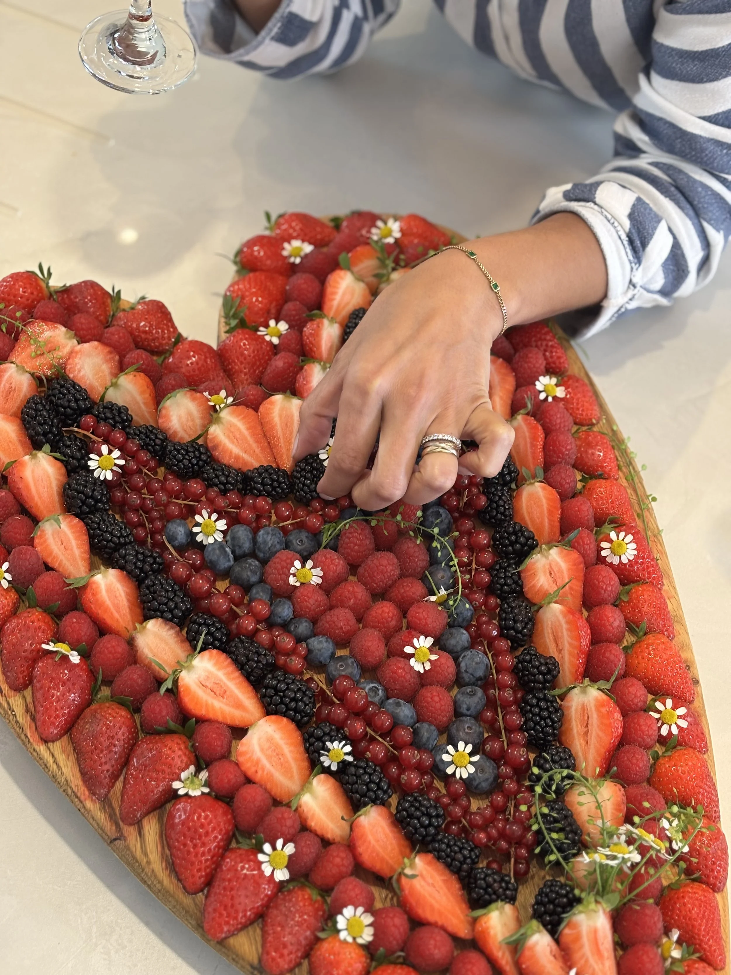 Plate de fruits rouges avec fraises, framboises, mûres, myrtilles, groseilles, décorée de petites fleurs blanches.