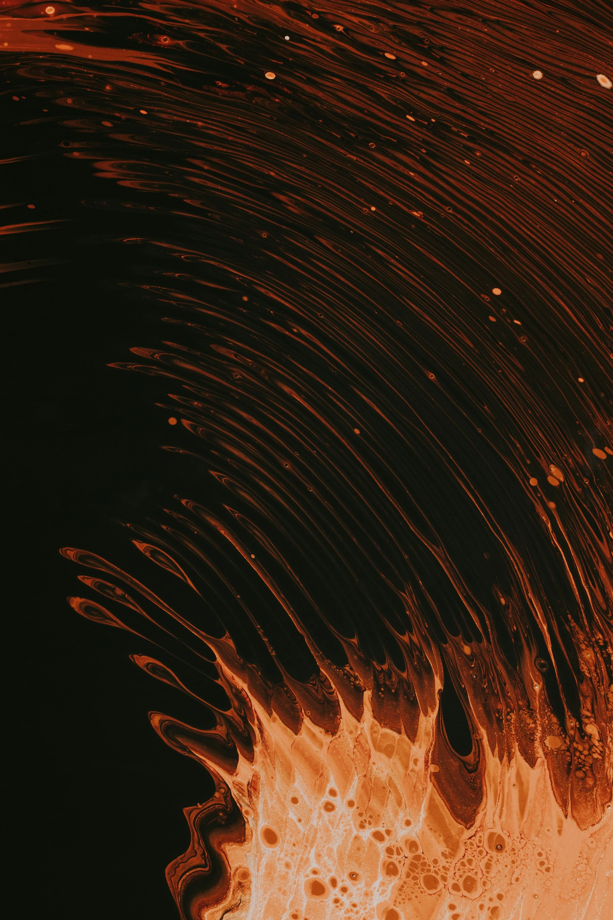 An abstract image with swirling patterns of orange, black, and white, resembling flowing liquid or paint.
