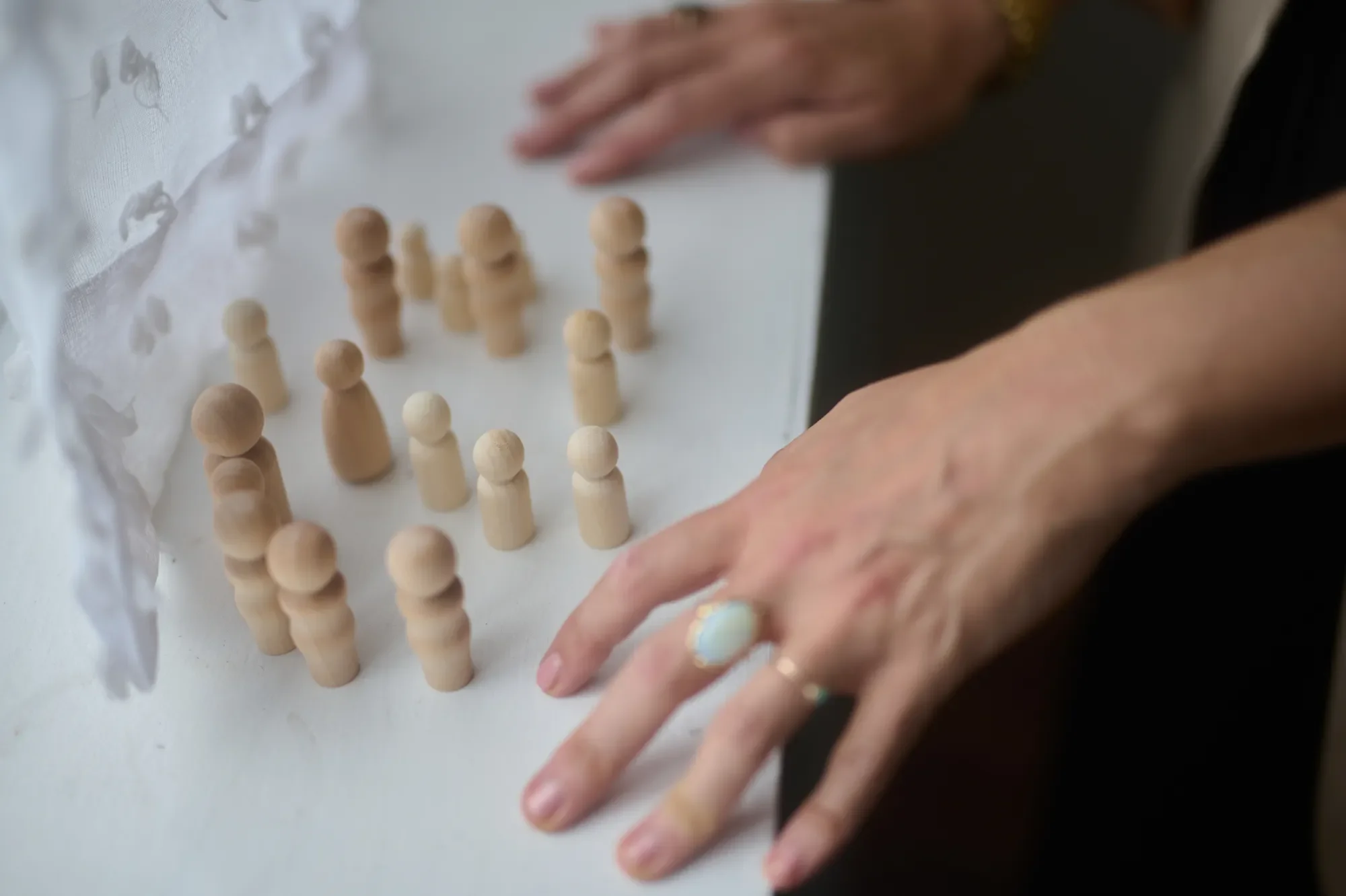 Close-up of a person's hands arranging wooden game pieces on a white surface.