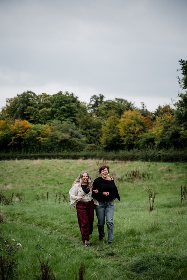 Two women walking through the countryside during a late summer gathering in Scotland.