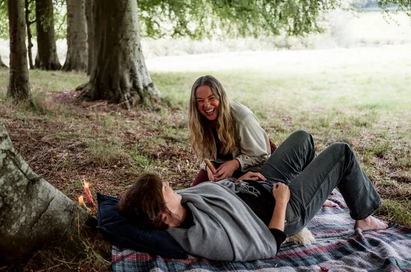 Two women laughing beneath the trees during a seasonal outdoor gathering in Scotland.