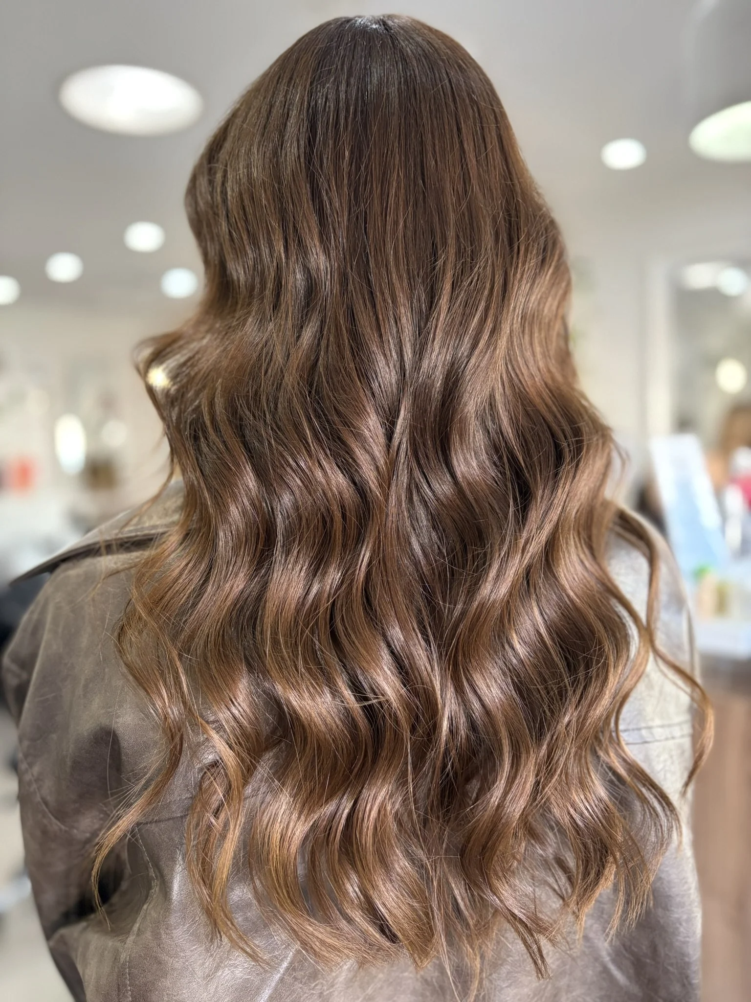 A person with long, wavy, reddish-brown hair in a salon.