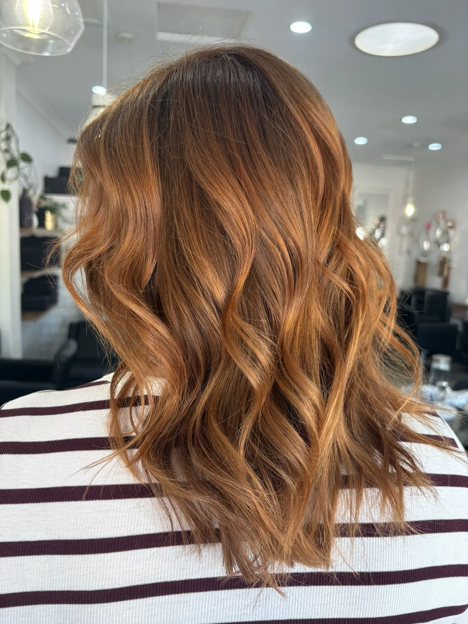 Close-up of a woman's head with long, wavy, red hair in a hair salon