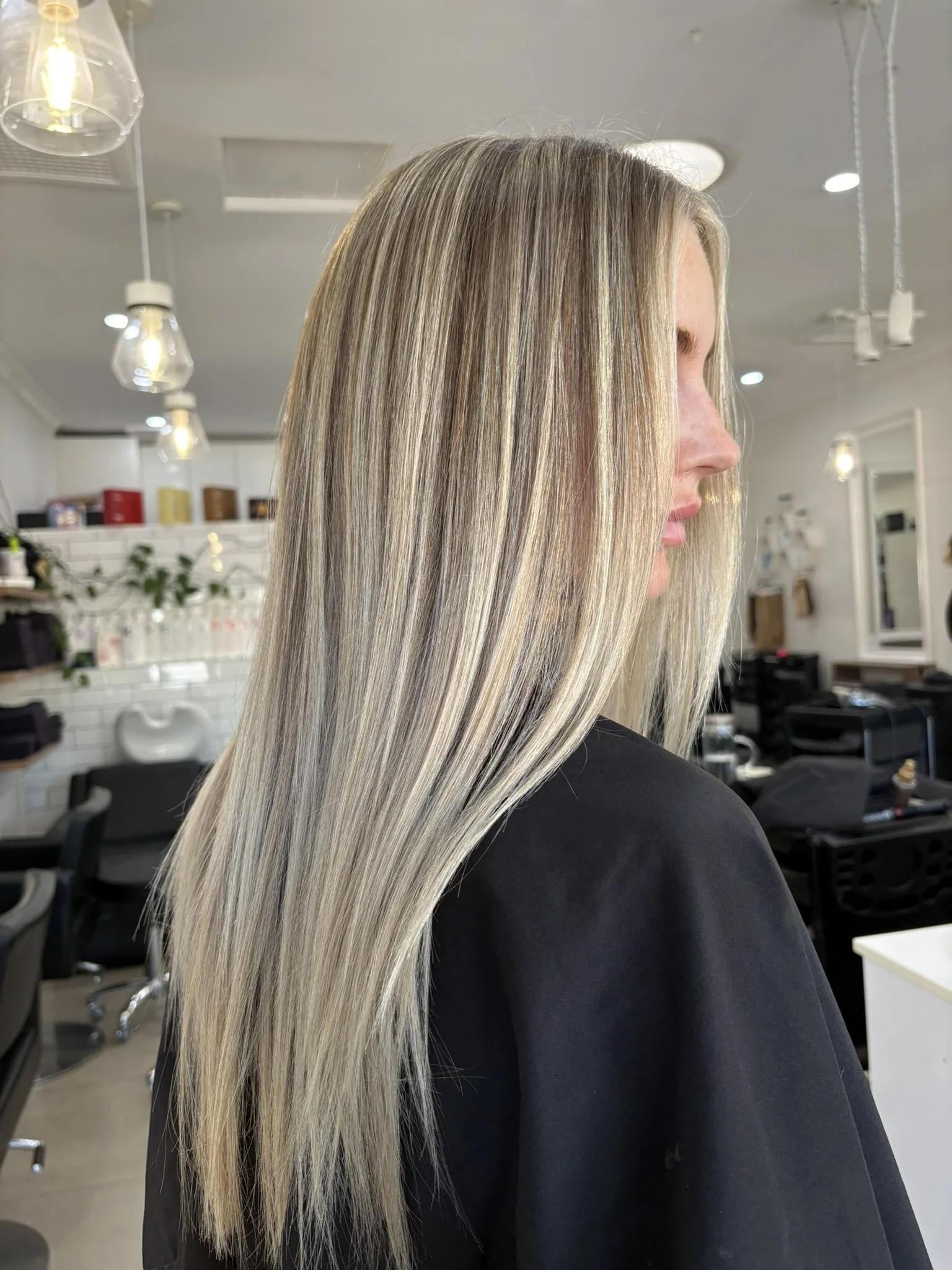 A woman with long, straight, multi-colored blonde hair in a salon.