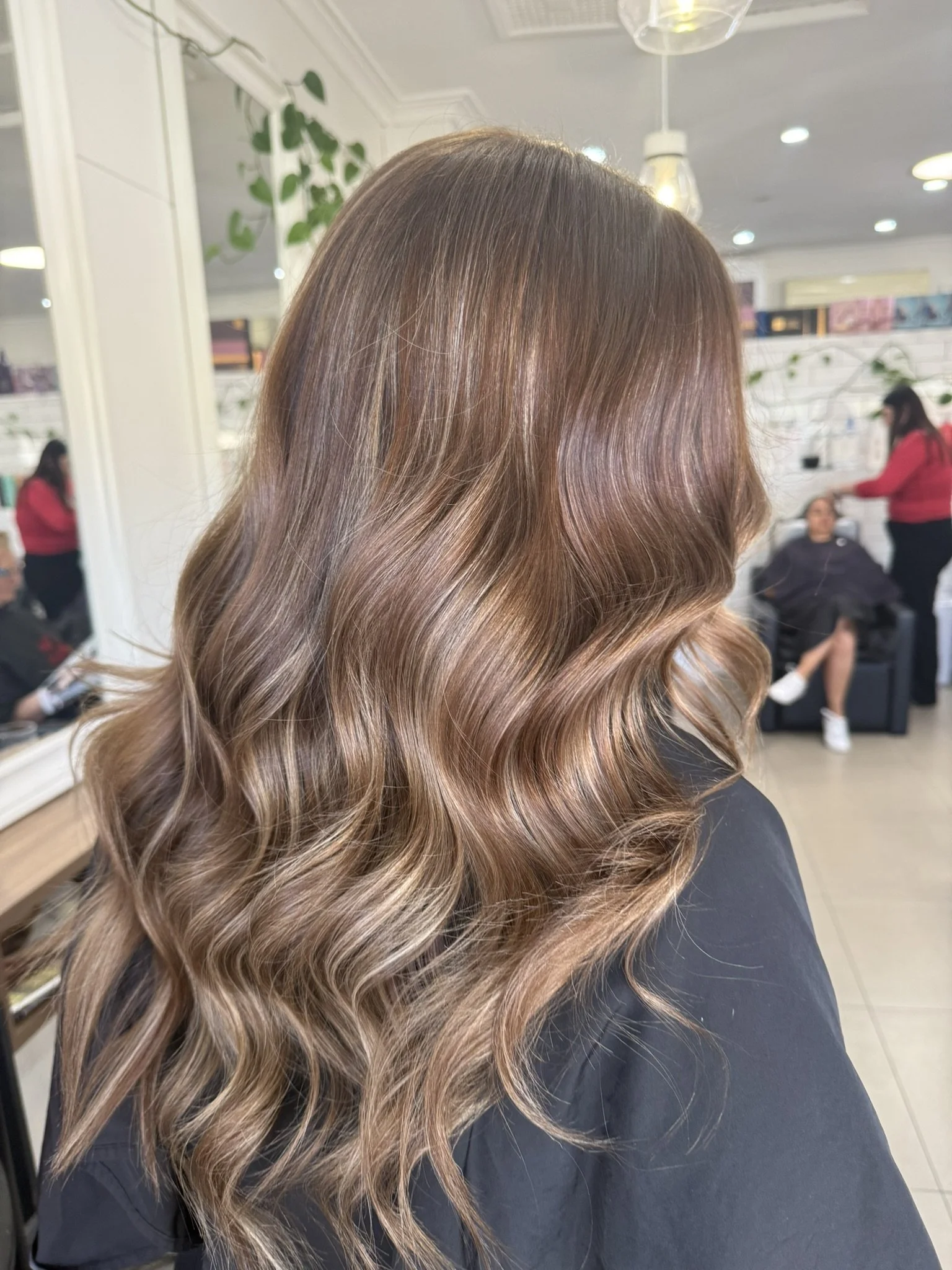 Close-up of a woman's long, wavy, highlighted hair in a salon.