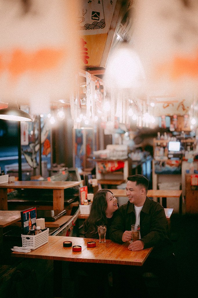 A couple sitting at a restaurant table, smiling and enjoying drinks together.