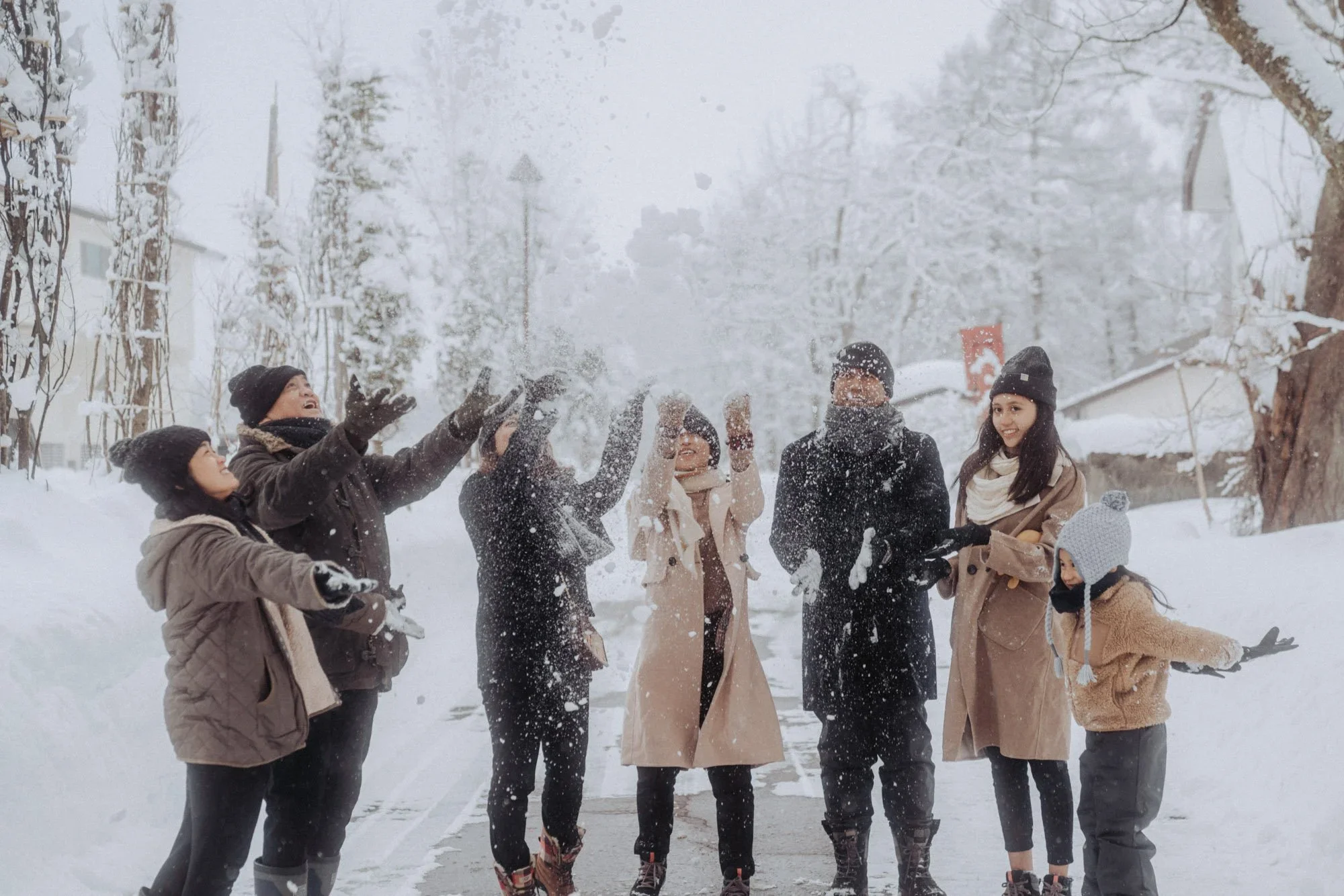 Group of people enjoying a snowball fight outdoors on a snowy winter day.