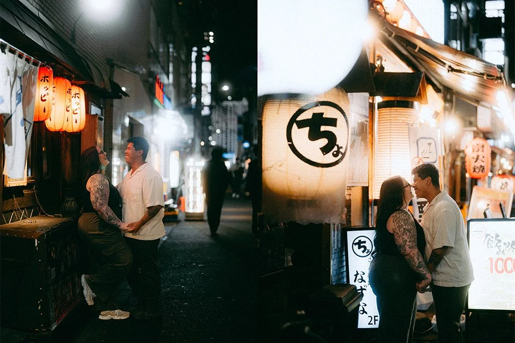 A couple stands close and faces each other in a narrow street lined with illuminated Japanese lanterns and signs, suggesting an evening scene in Japan.