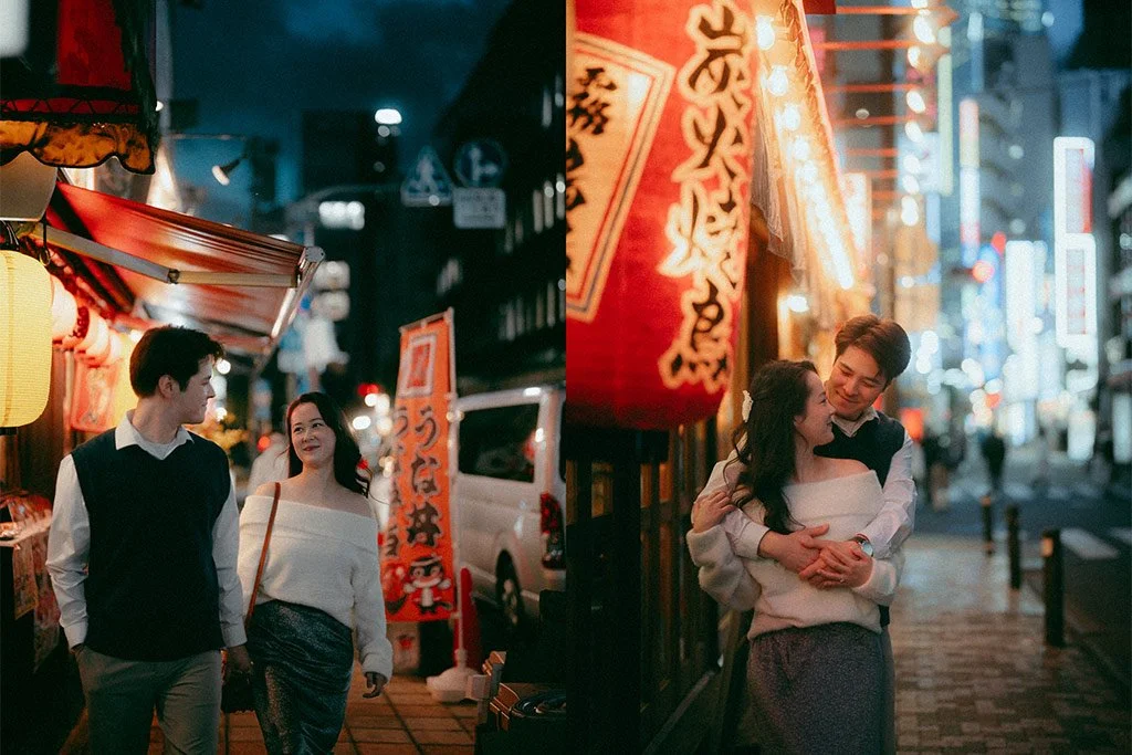 A young couple walking and smiling at night on a city street decorated with bright lanterns and signs, possibly in Japan.