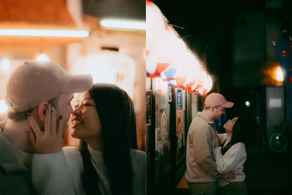 A young couple sharing a tender moment at night, standing close to each other, with the woman touching the man's face, in front of illuminated signs, possibly at a festival or street fair.
