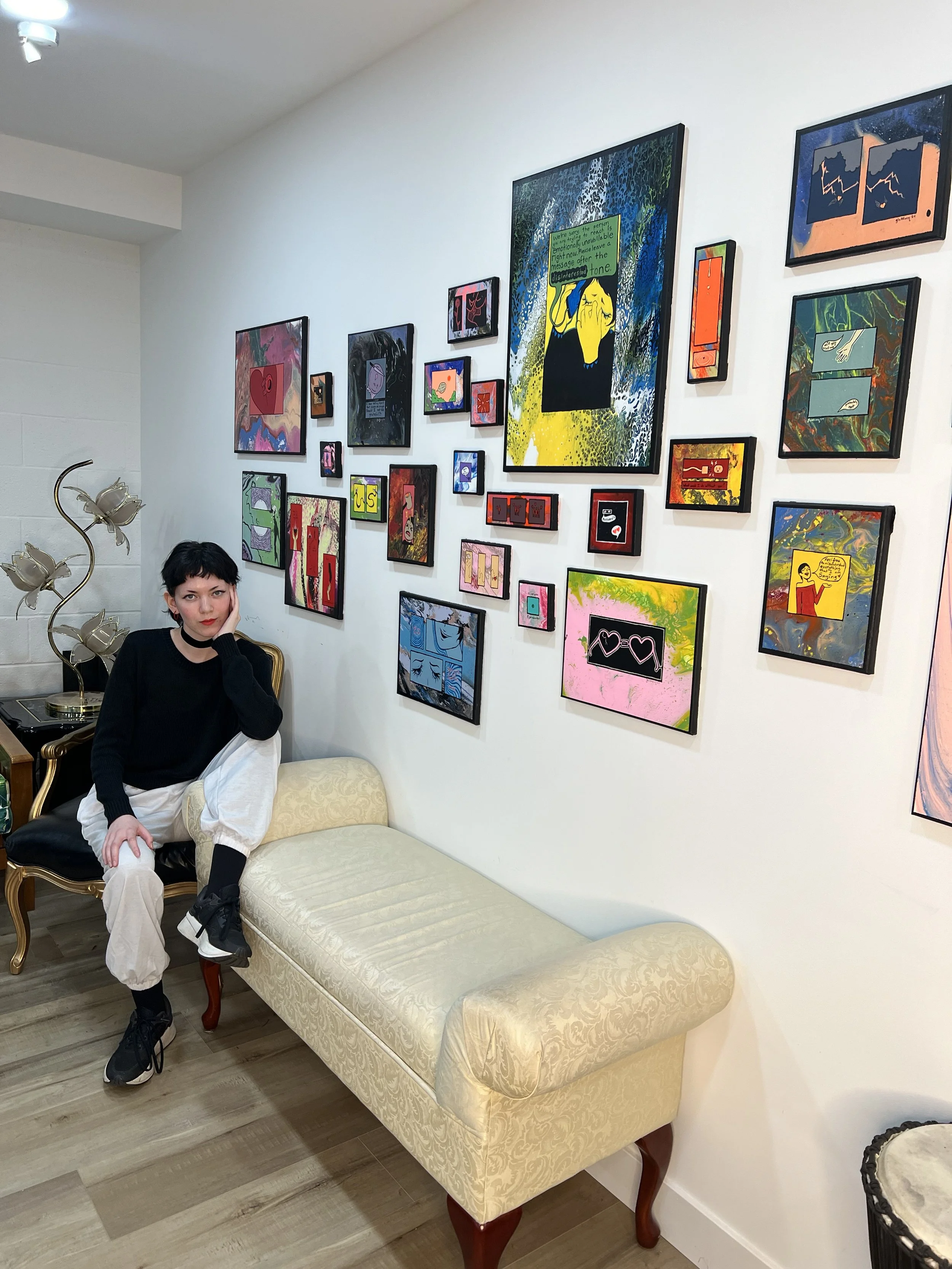 Rae Hofstedt sits next to the art exhibit "Hard Feelings" at GJ Studios Burbank in 2024.