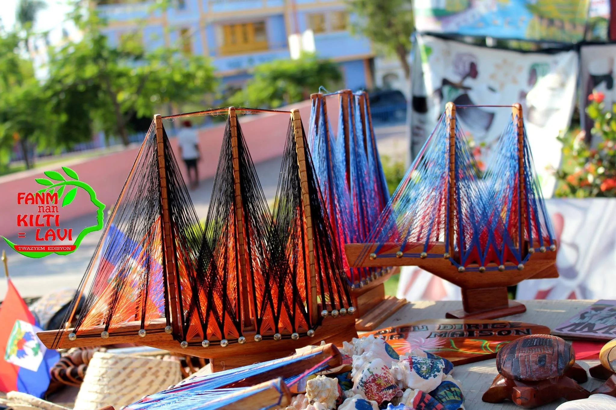 Vente d'objets artisanaux et souvenirs colorés en plein air, avec des modèles traditionnels en bois et fil de tissu coloré, au marché ou festival en plein air.