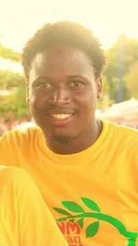 Un jeune homme souriant portant un t-shirt jaune avec un logo vert.