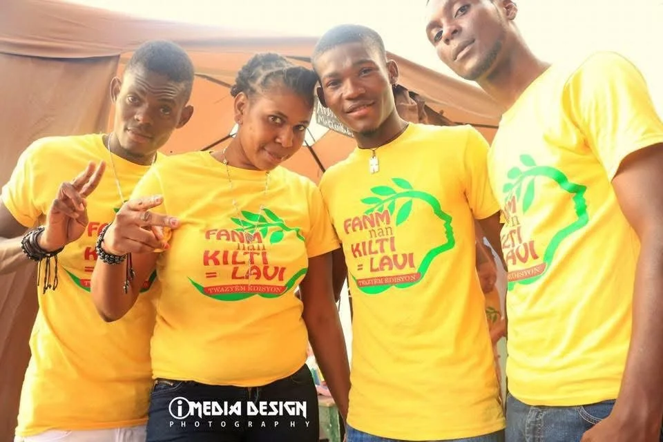 Quatre jeunes portant des t-shirts jaunes avec un logo et du texte, posant pour une photo lors d'un événement