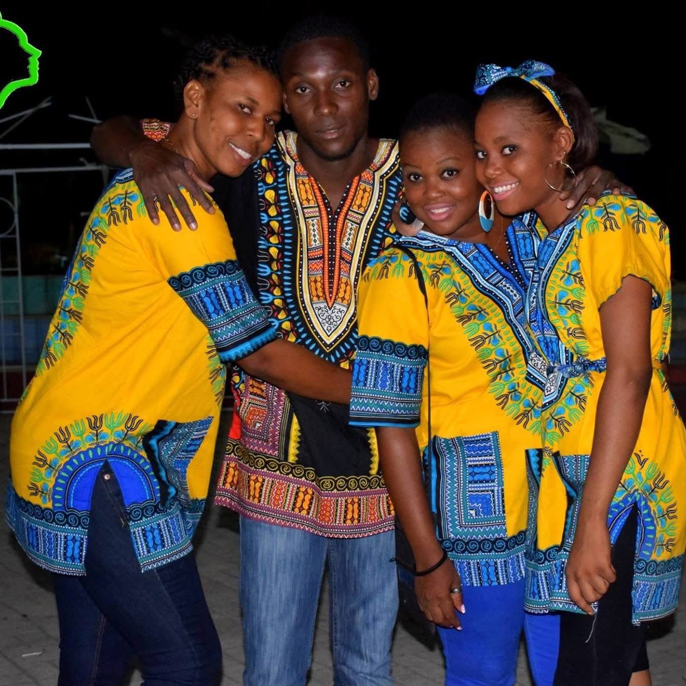 Groupe de quatre personnes portant des vêtements traditionnels colorés et décorés avec des motifs africains, souriants et posant pour une photo, apparemment lors d'une célébration ou d'un événement festif.
