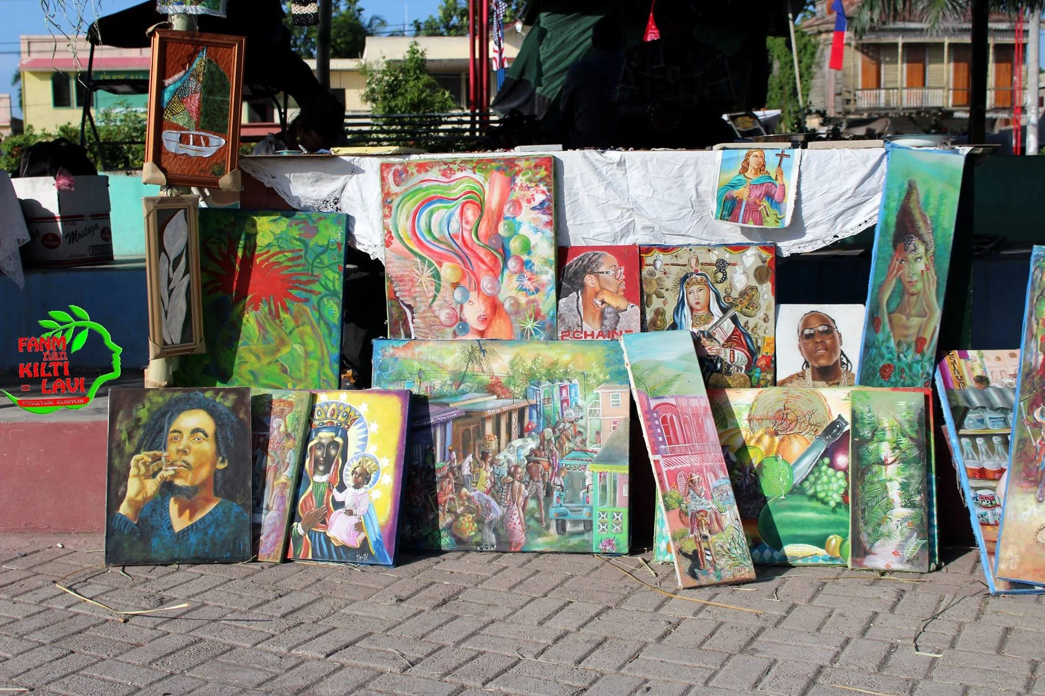 Vente d'œuvres d'art peintes à la main exposées sur un stand en plein air. Les tableaux incluent des portraits, des paysages et des œuvres abstraites, avec une variété de styles et de couleurs.