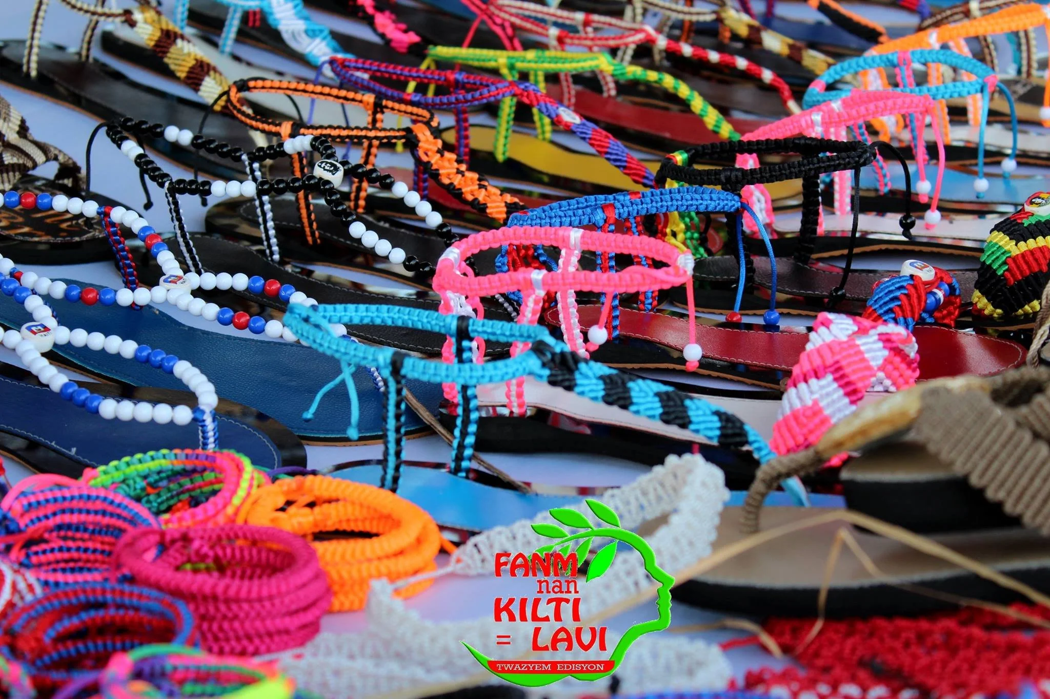Bracelets et sandales colorés en vente sur un stand lors d'un marché local, avec un logo d'une région du Kenya mentionnant 'Kiliti Laavi'.