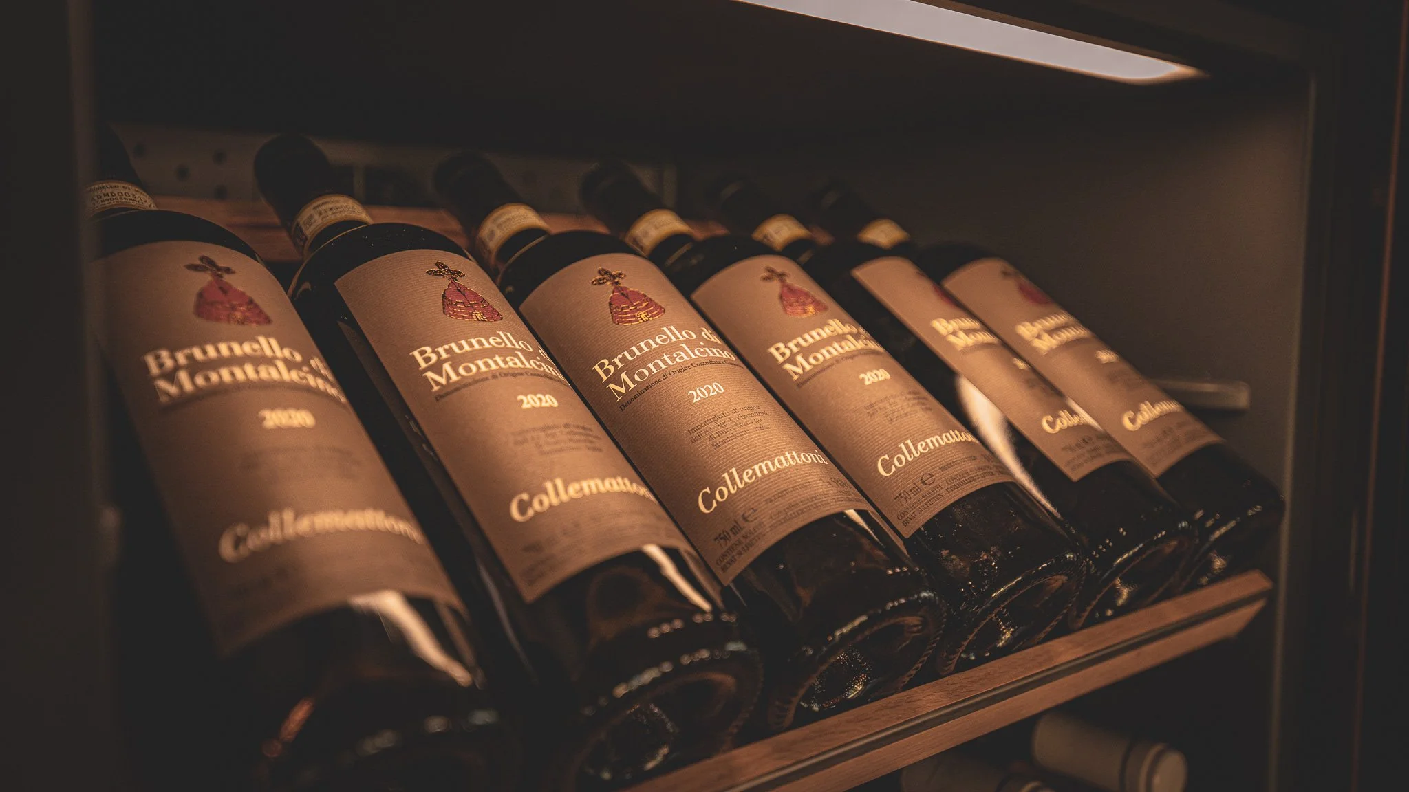Flasche Wein mit dem Etikett "Brunello di Montalcino 2020" vom Weingut Collemanto, im Weinregal liegend.