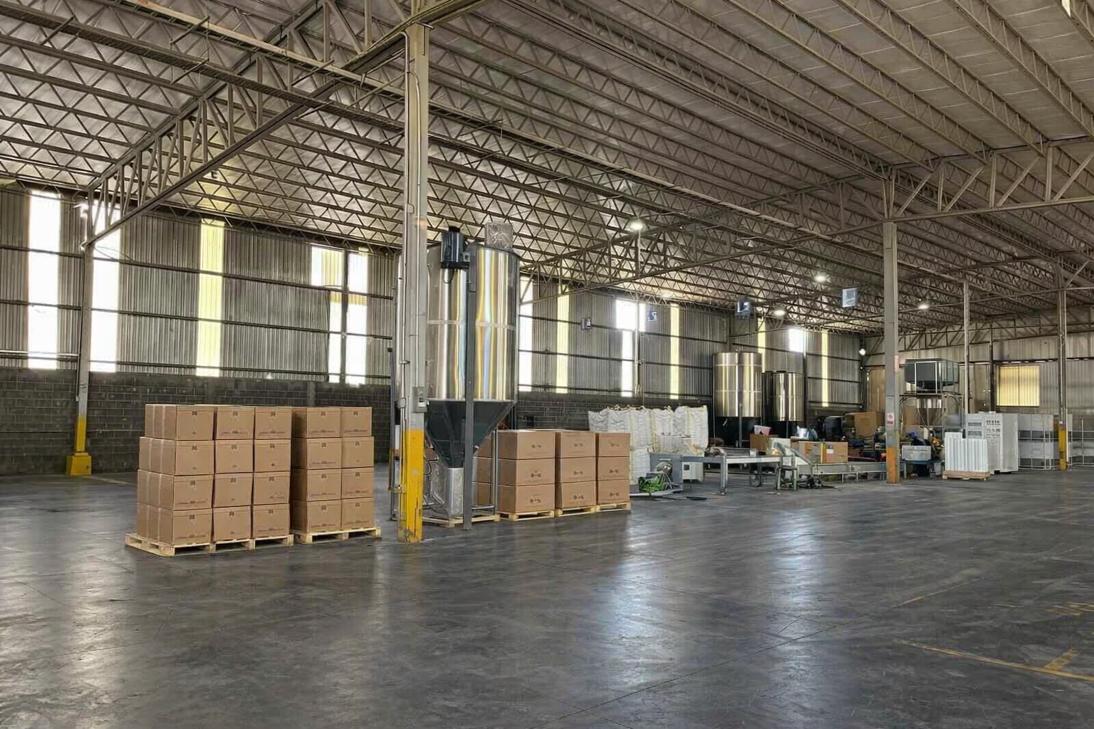 Interior de un almacén grande con cajas y máquinas de procesamiento.