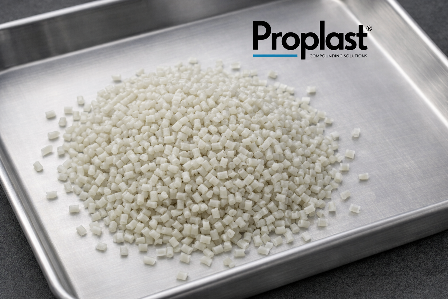 Pequeñas piezas blancas en una bandeja de acero, con el logo de Proplast y el texto 'COMPOUNDING SOLUTIONS'.