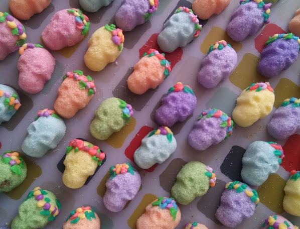 Colorful, candy-coated gummy candies with sprinkles arranged in rows on a tray.