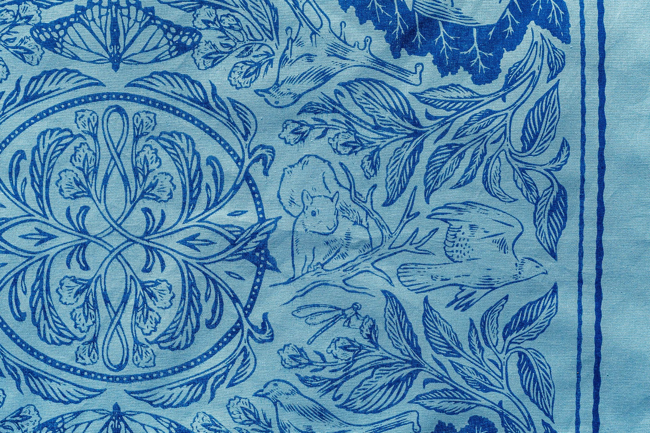Close-up of a blue and white fabric with intricate floral and butterfly patterns.