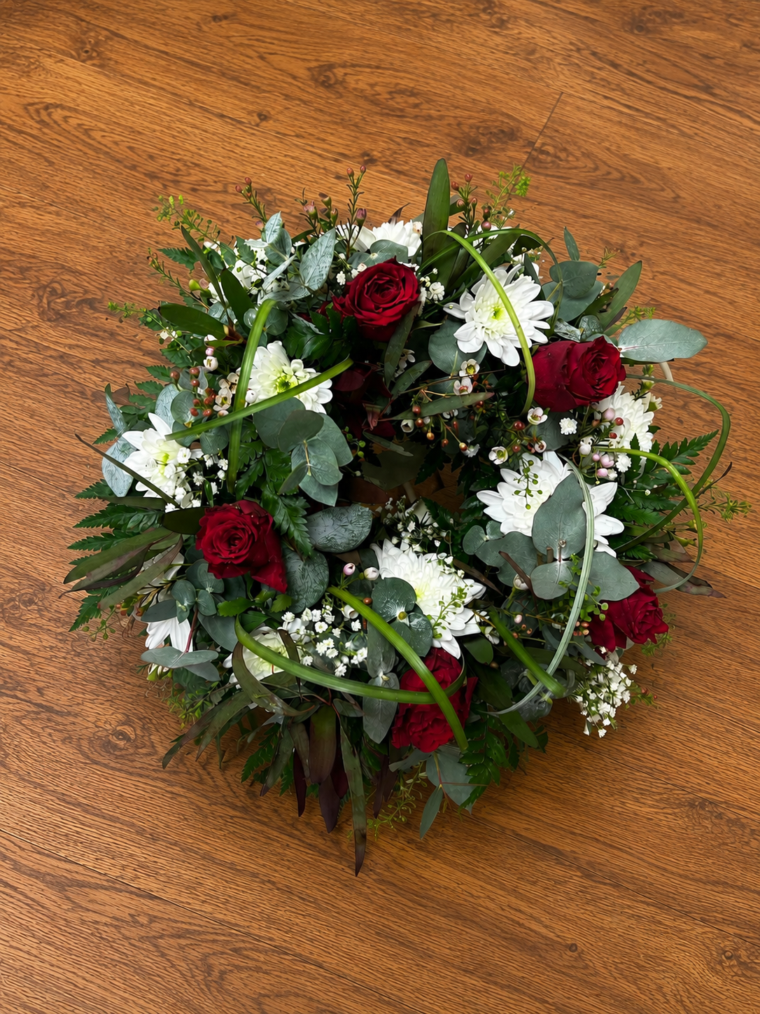 Red and white remembrance funeral bouquet with poppies, roses, carnations and daisies.