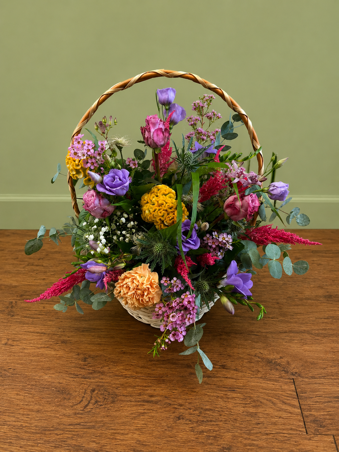 Colourful flower basket with pink roses, purple lisianthus, yellow celosia and eucalyptus.