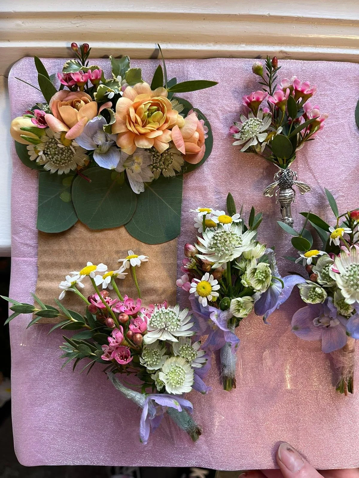 Arrangement of fresh flowers including roses, daisies, and other blossoms on a pink surface.