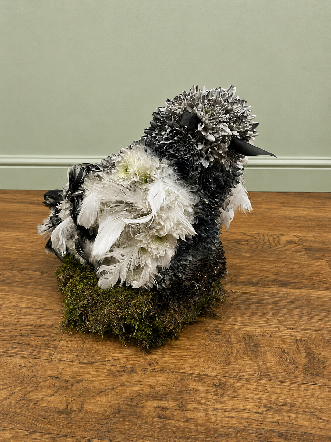 Bespoke penguin-shaped funeral tribute made with black and white chrysanthemums and feathers.