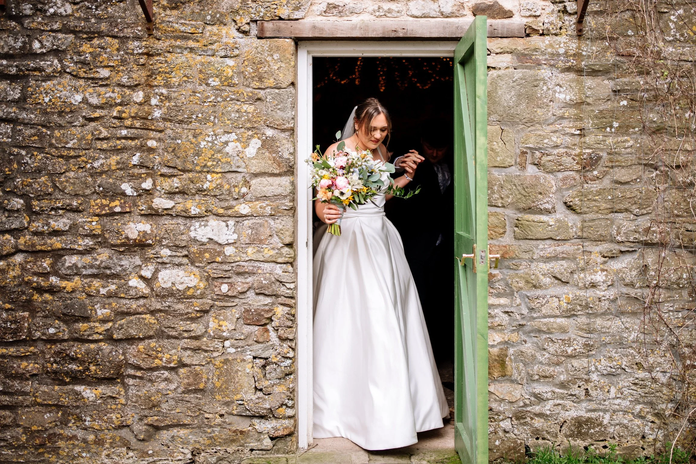 Bride holding a colourful bridal bouquet with pink, yellow and white flowers at a South West wedding.