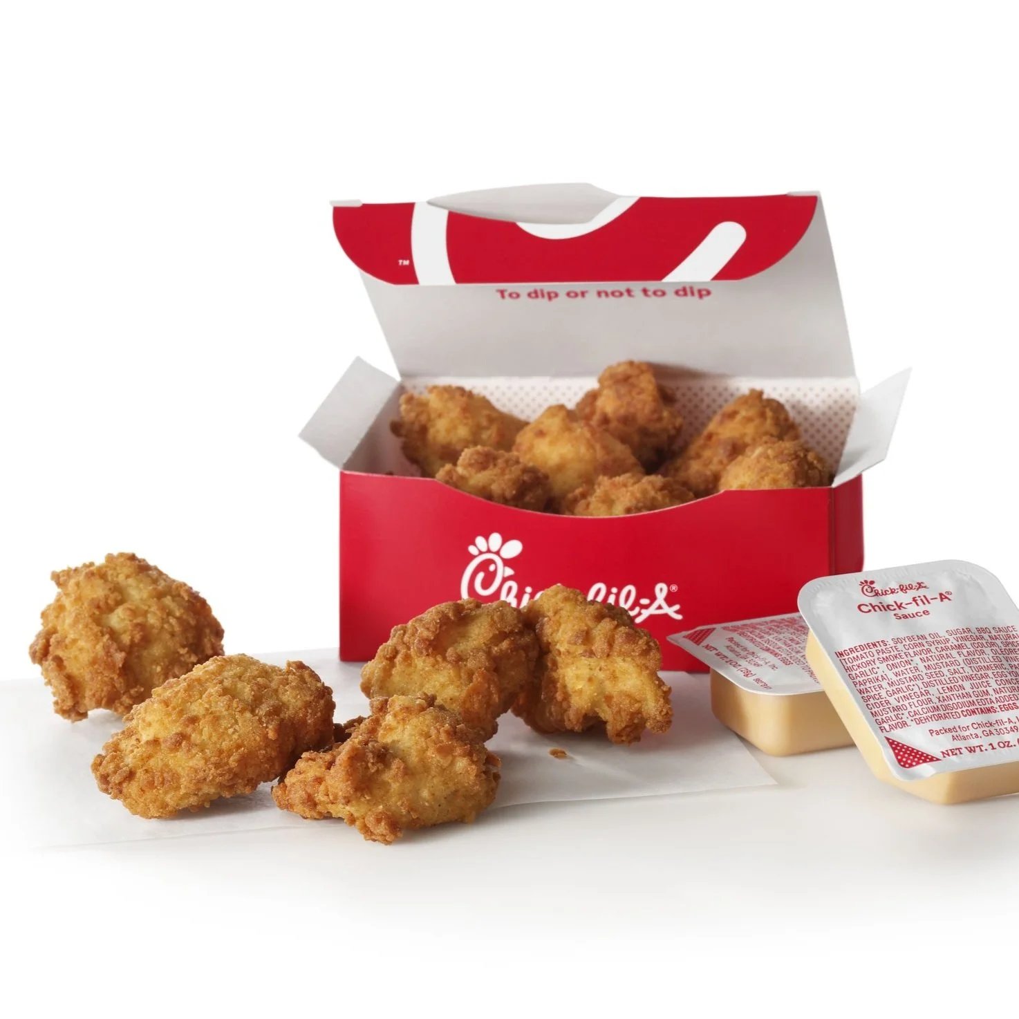 A box of Chick-fil-A nuggets with a few scattered on white paper, along with two containers of dipping sauce.