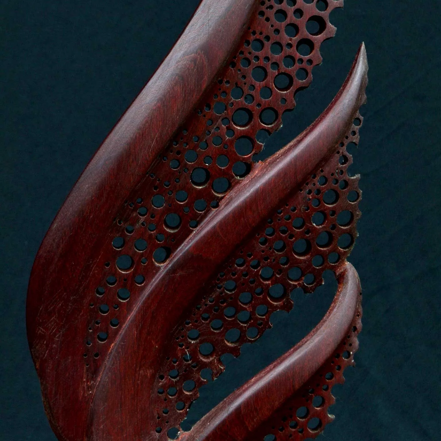 Close-up of the hand-carved perforations and flowing organic forms of the Organika wood sculpture by Patrick Hüttlinger.