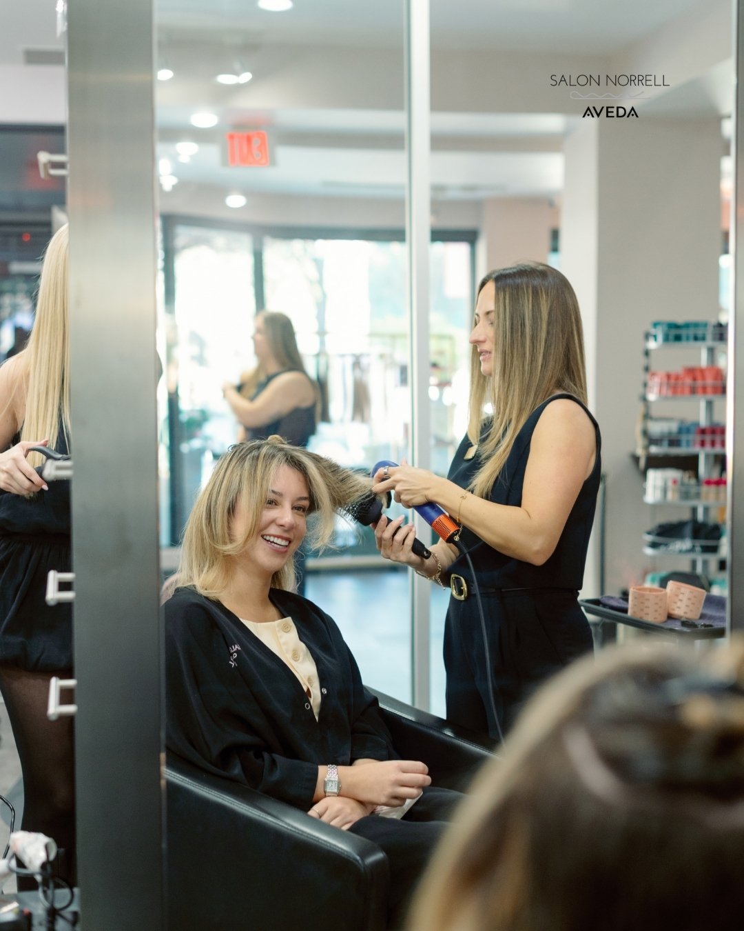 Kira — blonding and balayage specialist at Salon Norrell AVEDA in Hyde Park Tampa doing a bouncy blowout on model